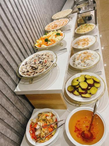 einem langen Tisch mit verschiedenen Lebensmitteln in der Unterkunft Valencia Da Nang Beach Hotel in Đà Nẵng