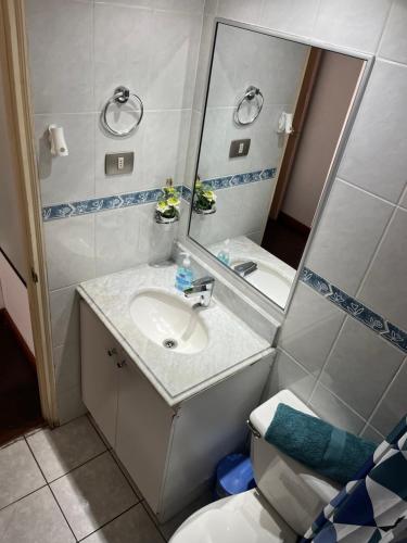 y baño con lavabo, espejo y aseo. en Aguamarina,Apart, en Iquique