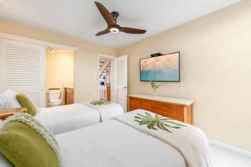 a bedroom with two beds and a ceiling fan at Kulakane 310 · KK 310 Updated BeachFront 2BD w AC Pool in Kahana