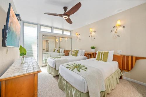 a bedroom with two beds and a ceiling fan at Kulakane 310 · KK 310 Updated BeachFront 2BD w AC Pool in Kahana