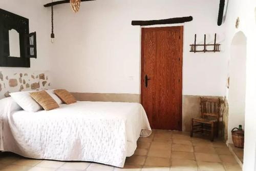 a bedroom with a white bed and a wooden door at Casa Rural La Corretger in Chulilla
