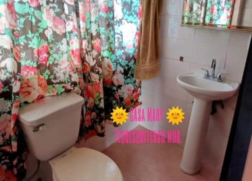 a bathroom with a toilet and a sink with a flower shower curtain at CASA MARY in Tequesquitengo