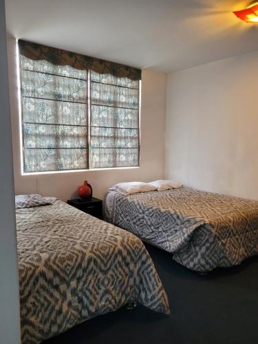 a bedroom with two beds and a window at Magicperu Apart Hotel in Trujillo