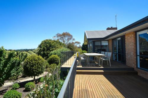 a house with a wooden deck with a table on it at Summerland in Merricks