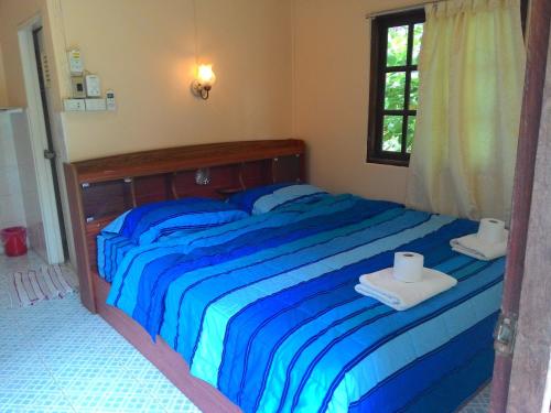 a blue bed with two towels and a window at Blue Lotus Resort in Ban Tai