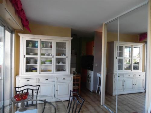 cocina con armarios blancos, mesa y sillas en Studio Canet-Plage, 1 pièce, 4 personnes - FR-1-750-2 en Canet-en-Roussillon