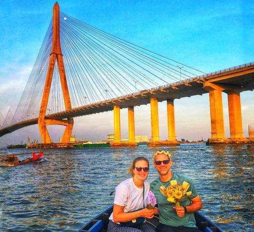 a man and woman in a boat on the water with a bridge at Bamboo Eco Village in Can Tho