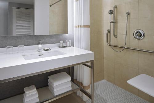 La salle de bains est pourvue d'un lavabo blanc et d'une douche. dans l'établissement Halifax Marriott Harbourfront Hotel, à Halifax