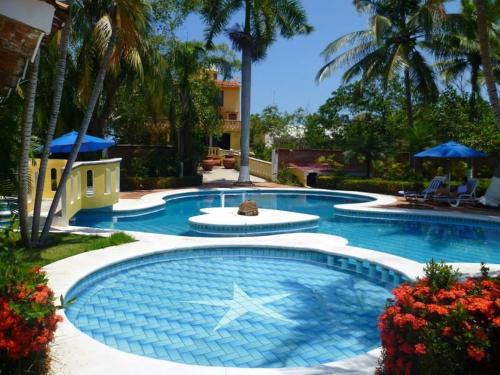 a large swimming pool in a yard with palm trees at Villa Corona del Mar in Rincon de Guayabitos