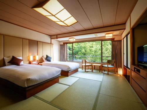 蔵王温泉にある蔵王四季のホテルのベッド2台とテレビが備わるホテルルームです。