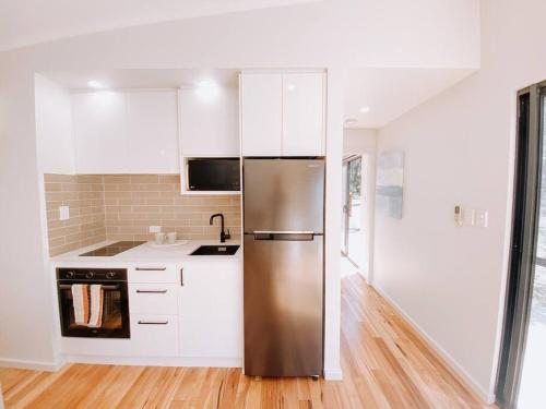 a kitchen with a stainless steel refrigerator and white cabinets at Wren Studio - Private One-Bedroom Studio Nestled in Bushland in Yallingup