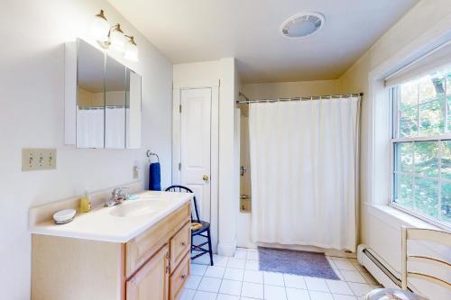 La salle de bains blanche est pourvue d'un lavabo et d'une fenêtre. dans l'établissement Harbor House B, à Camden