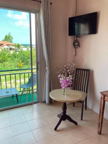 a table and a chair with a vase of flowers at Guest house Helene in Kata Beach