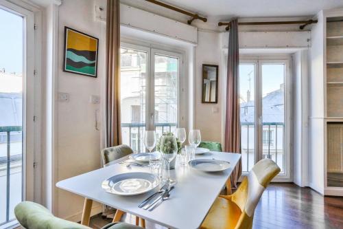 une salle à manger avec une table et des chaises blanches dans l'établissement Appartement Quartier Saint Michel Free Netflix, à Paris