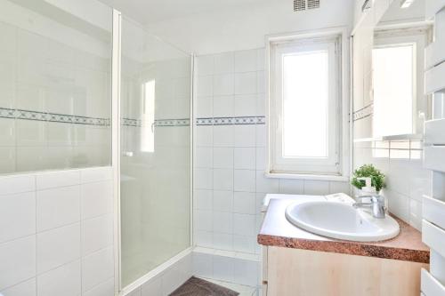une salle de bain blanche avec un lavabo et une douche dans l'établissement Appartement Quartier Saint Michel Free Netflix, à Paris