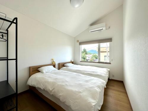 two beds in a small bedroom with a window at ADVENTURe (アドベンチャー) in Furano