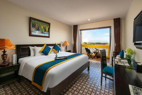 a hotel room with a large bed and a balcony at La Charm Hoi An Hotel & Spa in Hoi An