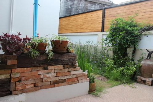 a garden with potted plants on a brick wall at Tree Home Plus in Nakhon Si Thammarat