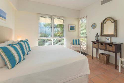 ein Schlafzimmer mit einem großen weißen Bett und einem Schreibtisch in der Unterkunft No 3 @ The Hill Apartments in Port Douglas