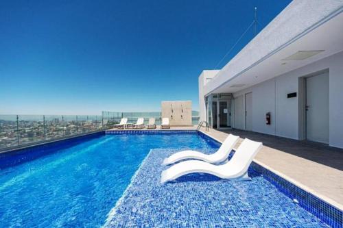 - une piscine avec 2 chaises blanches dans un bâtiment dans l'établissement 0509 iFreses Hermoso Apartamento con Aire Acondicionado y Parqueo, à Curridabat