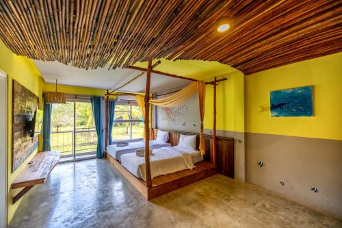 Dugong Village-Green Hotel في Pak Meng: غرفة نوم بسرير بأربعة أعمدة وجدران صفراء