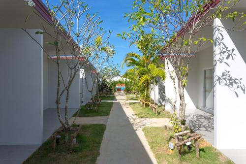 una pasarela entre dos edificios con árboles y bancos en Chongfah Mountain View en Khao Lak