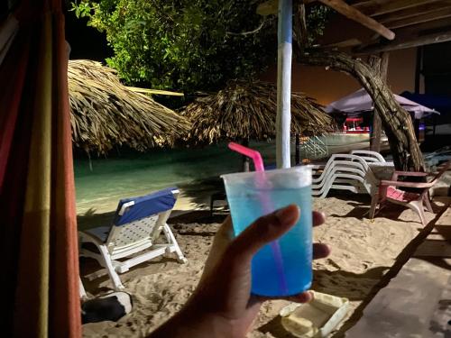 a hand holding a blue drink with a pink straw at Posada Shekinah Barú in Playa Blanca