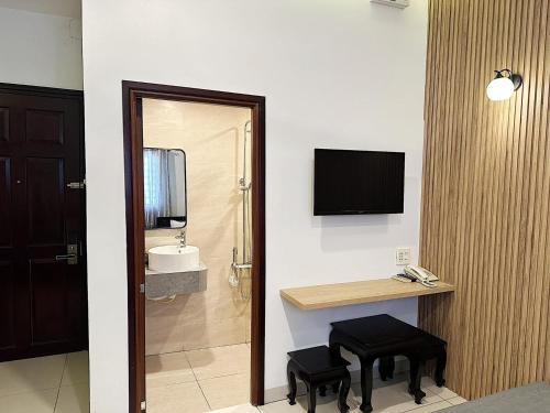 a room with a bathroom with a desk and a television at Phuong Nam Hotel An Giang in Long Xuyên
