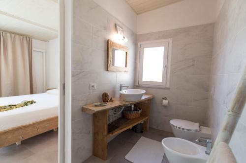 bagno bianco con lavandino e servizi igienici di Villa Michaela con piscina privata e vista mare a Capo Vaticano