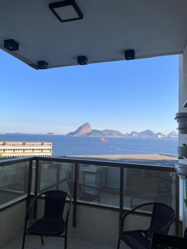 2 stoelen op een balkon met uitzicht op het water bij Apartamento Vista.Rio in Niterói