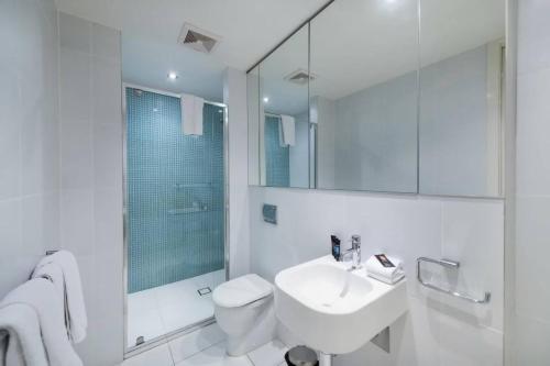 Baño blanco con lavabo y aseo en Trieste Apartments Kingston ACT, en Canberra