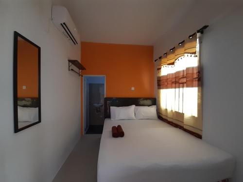 a bedroom with a bed with a pair of shoes on it at Capital O 93076 Batam Backpacker Guesthouse 2 in Pembunuh