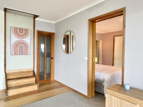 um quarto com uma porta que leva a uma cama e um espelho em The Beautiful Grand Terrace (Seaview) em Mount Martha