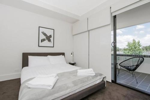 a white bedroom with a bed and a balcony at The Prince Lakefront Kingston ACT in Canberra