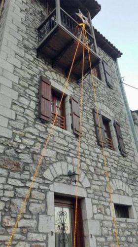 a tall stone building with windows and a balcony at Despotikon Dimitsana Guest house - Ξενώνας Δεσποτικόν Αντωνόπουλου in Dhimitsana