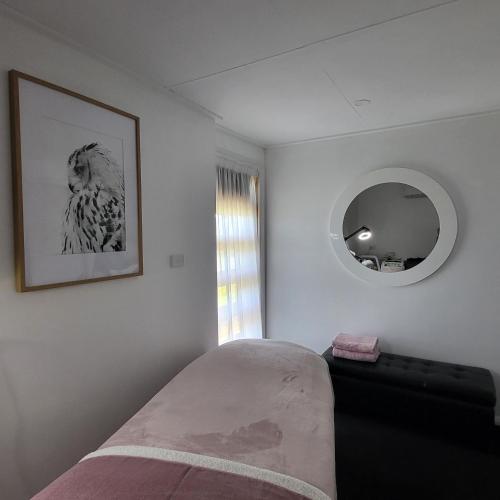 1 dormitorio con cama y espejo en la pared en Primrose Seaside Healing Retreat en Primrose Sands