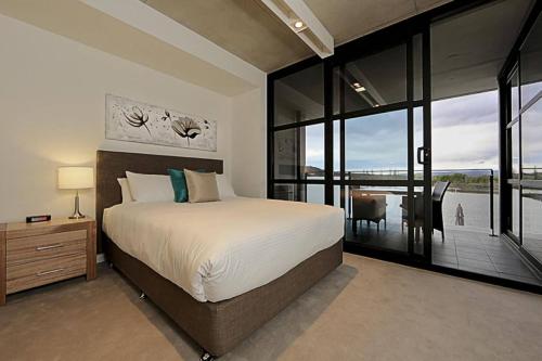 a bedroom with a large bed and a balcony at Dockside Apartments Kingston ACT in Canberra