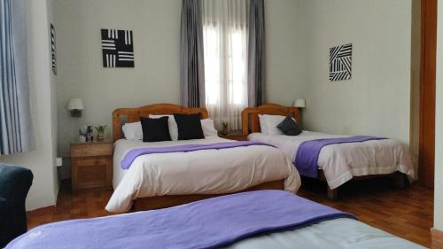 1 Schlafzimmer mit 2 Betten mit lila und weißen Laken in der Unterkunft Runcu Arequipa in Arequipa