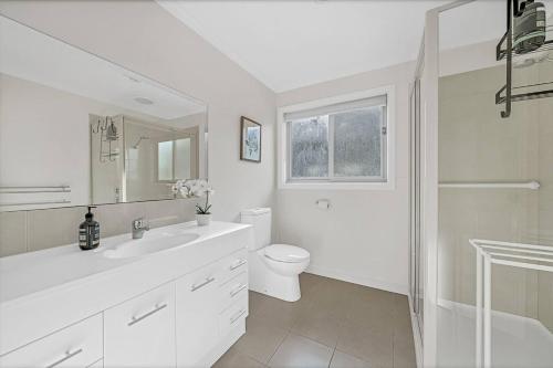 biała łazienka z toaletą i umywalką w obiekcie 'Hemmet House' A Smith Beach Locale with Ocean Views w mieście Rhyll