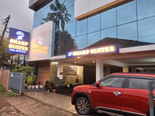 a red suv parked in front of a shopping center at Sharp Suites in Ernakulam