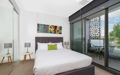 堪培拉IQ Smart Apartments 704 Braddon ACT的一间带床的卧室和一个带桌子的阳台