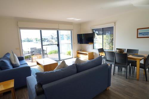 a living room with blue couches and a dining room at Captains Cove Resort - Waterfront Apartments in Paynesville