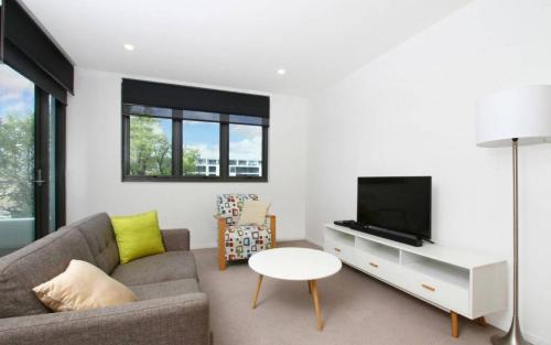 a living room with a couch and a tv at IQ Smart Apartments 507 Braddon ACT in Canberra