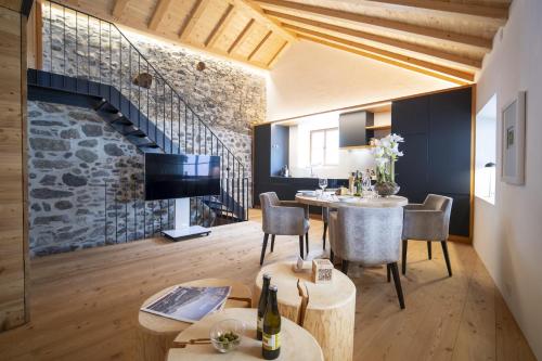 a living room with a table and chairs and a stone wall at Chasa Sömmi in Ftan