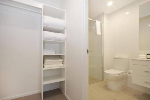 a white bathroom with a toilet and a shower at IQ Smart Apartments Braddon ACT in Canberra