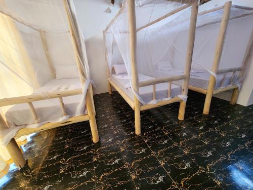 two wooden beds in a room with a tiled floor at Mkeka Spice Lodge Jambiani in Jambiani