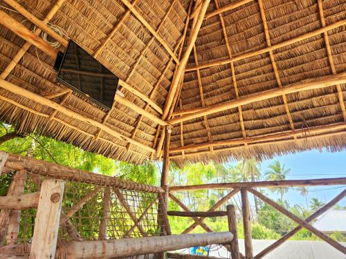 a straw roofed building with trees in the background at Mkeka Spice Lodge Jambiani in Jambiani