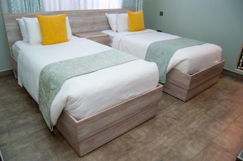 two beds in a hotel room with two at Bellwether Apartments in Kampala