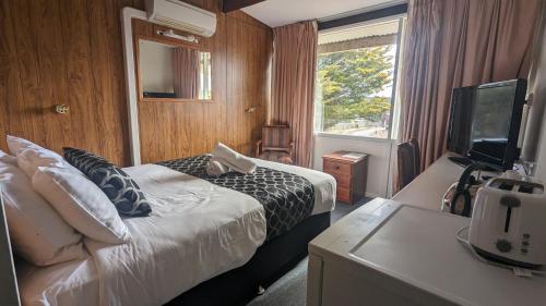 um quarto de hotel com uma cama e uma televisão em Cooma High Country Motel em Cooma