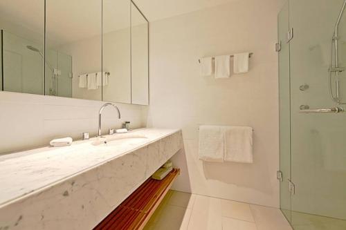 a white bathroom with a sink and a shower at Realm Park Barton ACT in Canberra